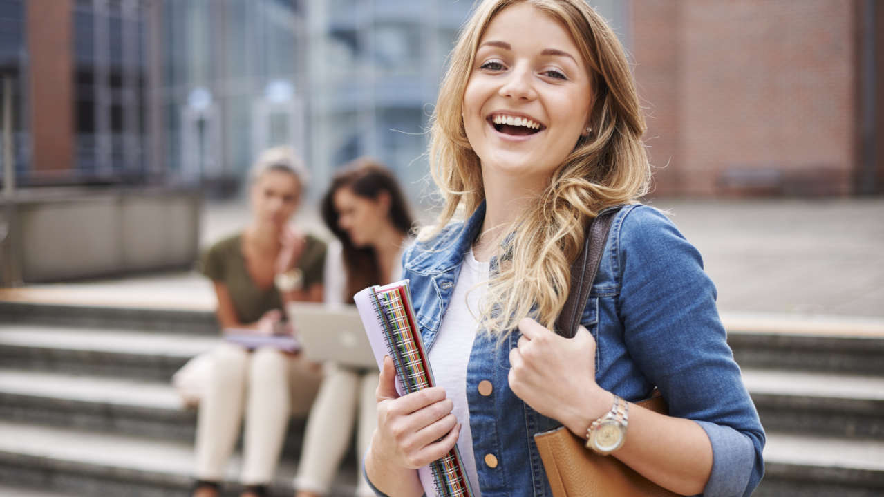 Jovem universitária com cadernos sorrindo por fazer parte do FIES Barão de Mauá 2025