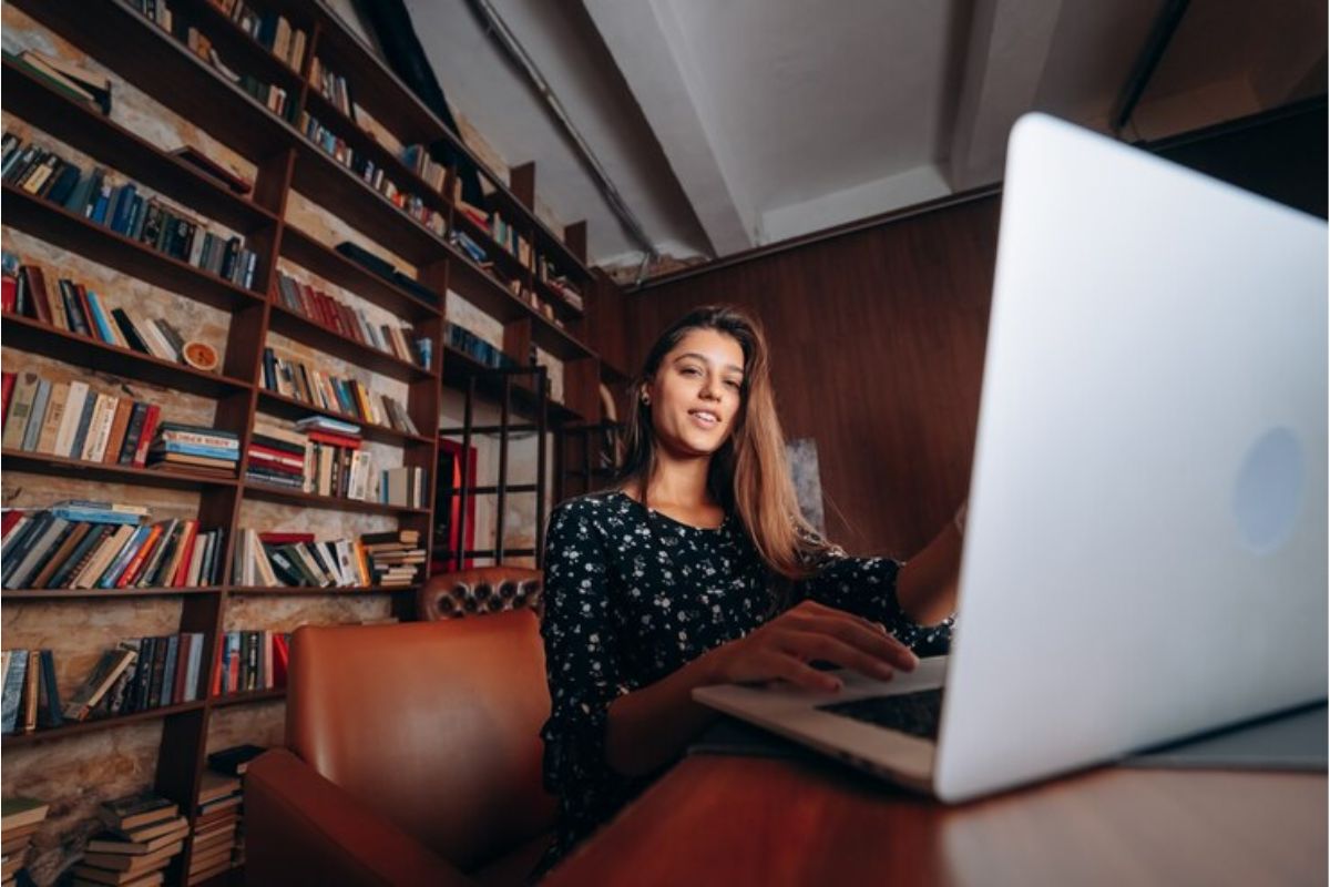 Uma menina sentada em frente ao seu notebook faz a rematrícula FIES 2025