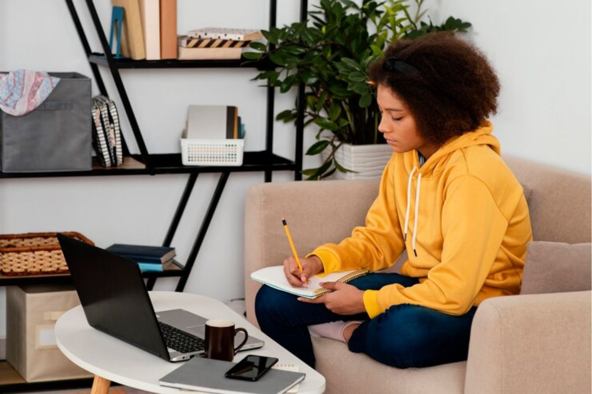 Uma estudante na sala da sua casa. Ela está em frente ao notebook onde se inscreve no FIES Social 2025