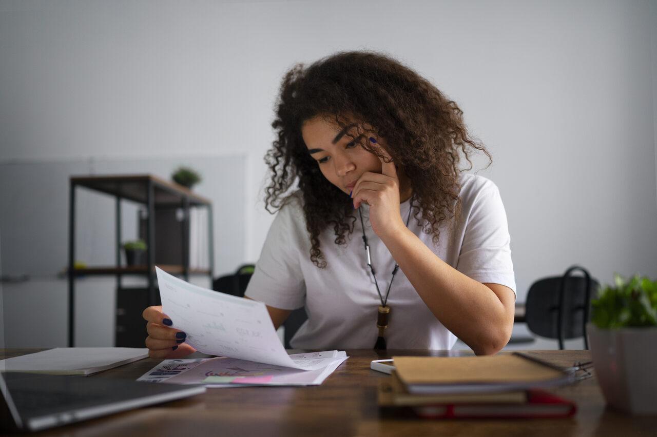 Jovem analisa papelada com expressão preocupada 