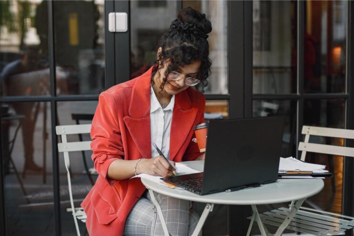 Uma jovem faz anotações em seu caderno após ver informações sobre o FIES em seu notebook