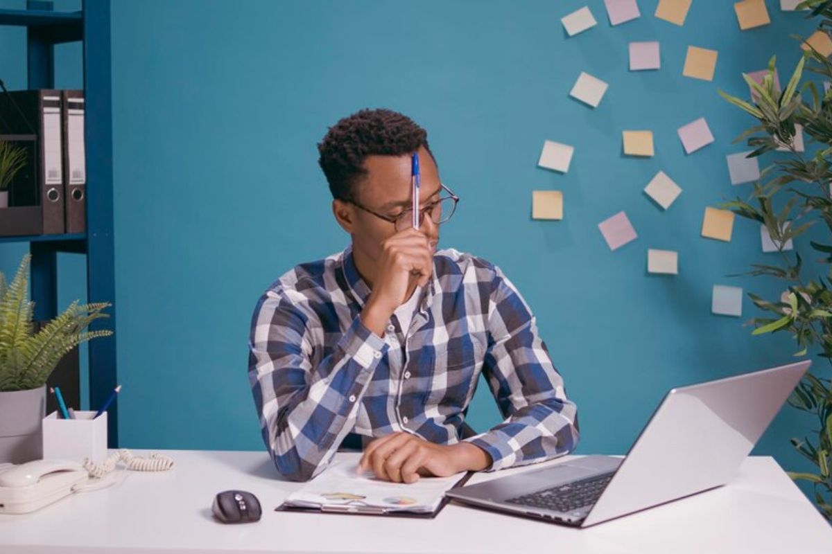 um jovem em frente ao seu notebook com uma caneta levantada pesquisa se FIES pode ser deduzido do Imposto de Renda