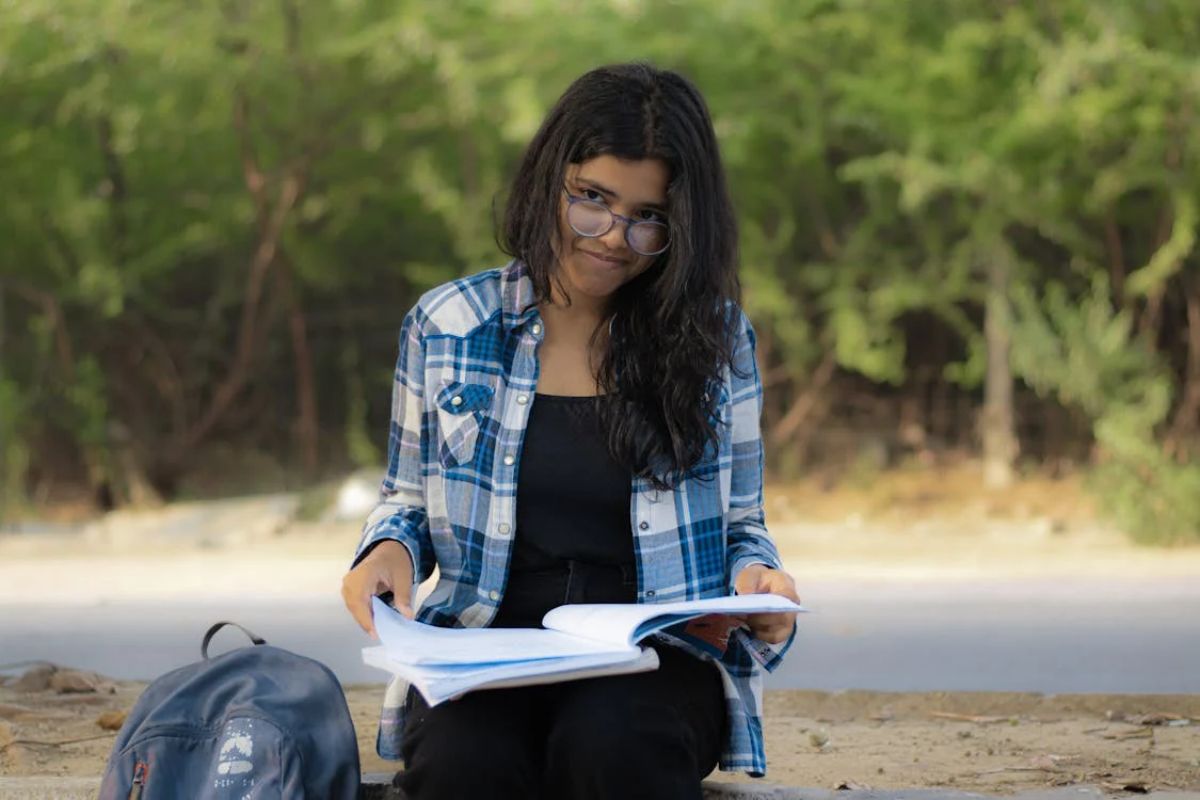 Uma estudante no jardim da universidade com o seu caderno aberto