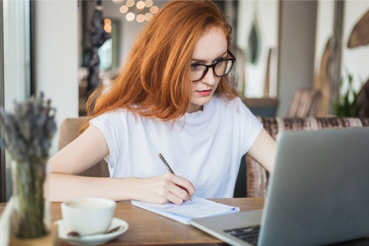 Uma estudante em frente ao notebook pesquisa quais as melhores faculdades do sul de Minas para conseguir FIES