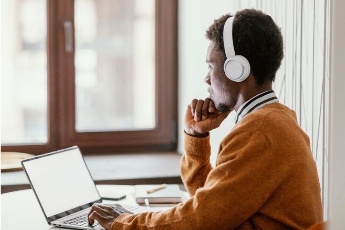 Um jovem em frente ao seu notebook com a mão no queixo se questiona se FIES pode ser deduzido do Imposto de Renda